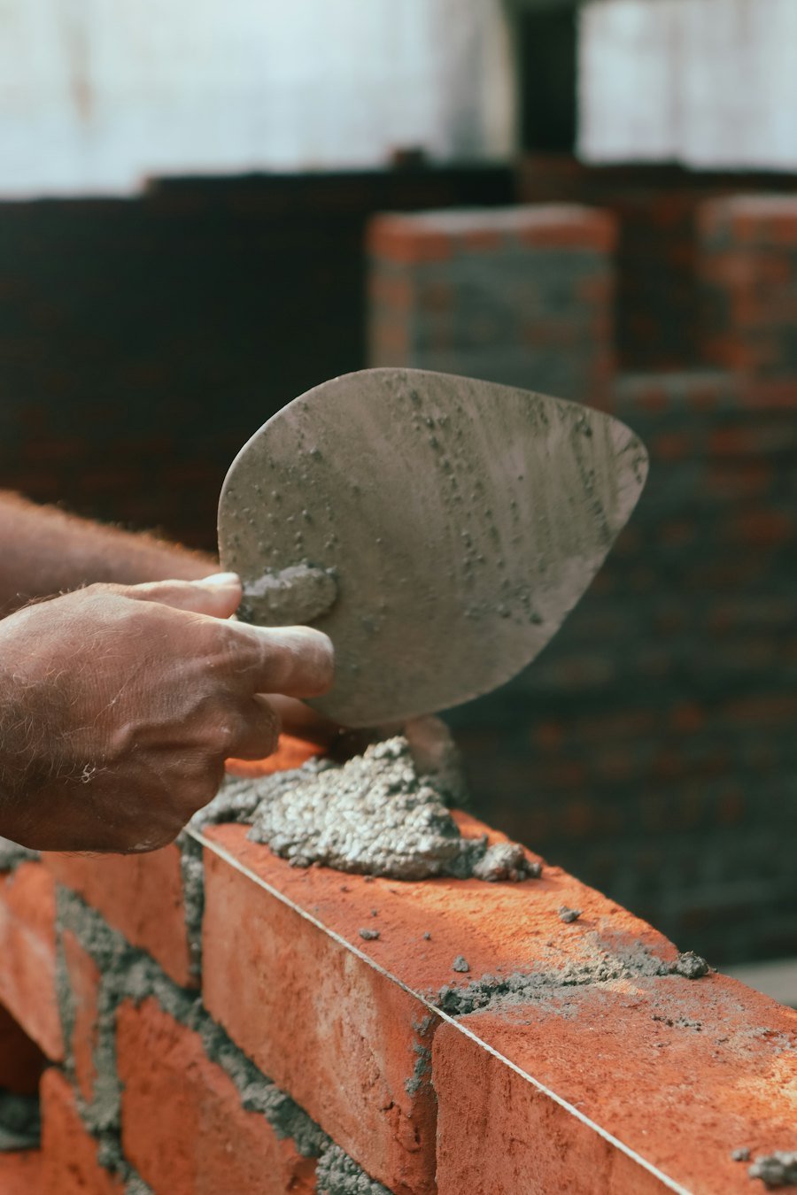 Zidar așezând mortar pe un perete de cărămidă cu mistria