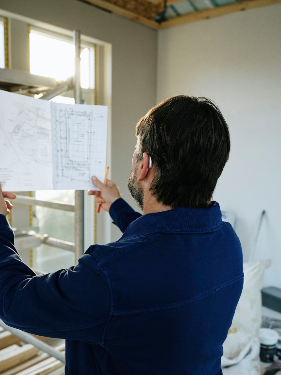 Meșter studiind planul unei lucrări într-o cameră în renovare