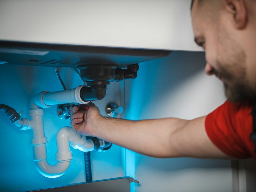 Instalator reparând sifonul de sub o chiuvetă