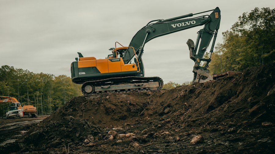Excavator nivelând un teren proaspăt curățat