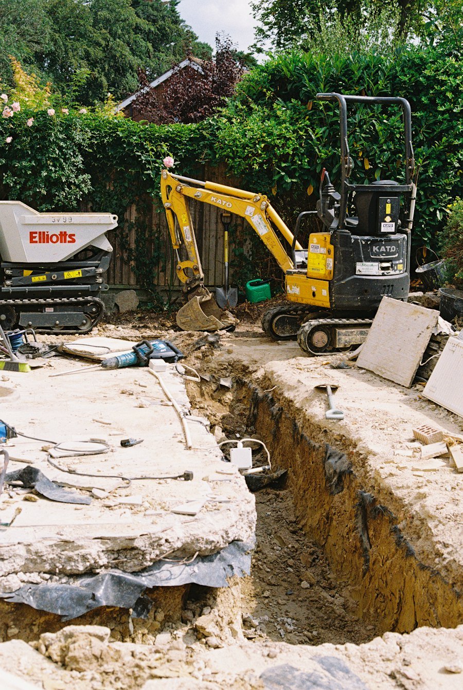Miniexcavator săpând un șanț lângă o casă
